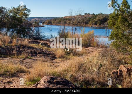 Texas Hill Country hiking trail with a view of Inks Lake. The path leads to the water in the Autumn sunlight.  Inks Lake State Park Burnet Texas. Stock Photo