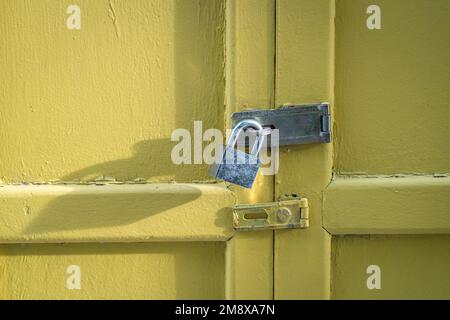 Yellow wood door closed with padlock. Security concept, copy space. Stock Photo