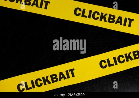 Clickbait scam alert, caution and warning concept. Yellow barricade tape with word clickbait in dark black background. Stock Photo