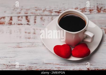 Cup of coffee and a couple of red hearts. The concept of greeting card for Valentine's day Stock Photo