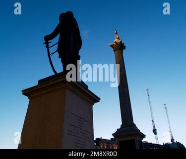 Sir Henry Havelock statue in silhouette and Nelsons Column partially lit. Dusk in Trafalgar Square, London Stock Photo