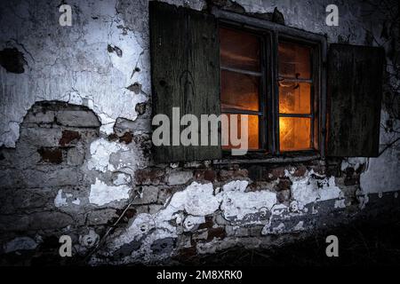 Old decayed wooden window on old house facade in candlelight ...