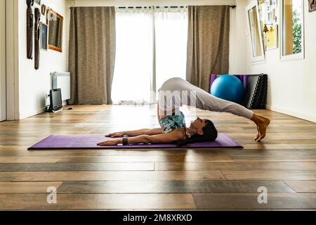Side view of a woman practicing yoga, doing Plow Pose (Halasana) pose Stock Photo