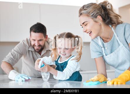 Little girl spraying the kitchen counter. Caucasian family cleaning the kitchen together. Happy family doing chores together. Cheerful family Stock Photo