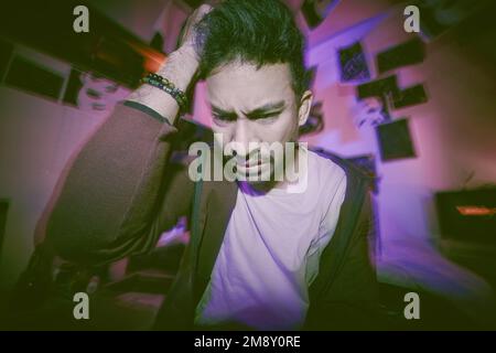 Asian man with mental disorder sitting alone at night feeling paranoid. Mixed race man mentally ill, feeling depressed and holding chest in his Stock Photo