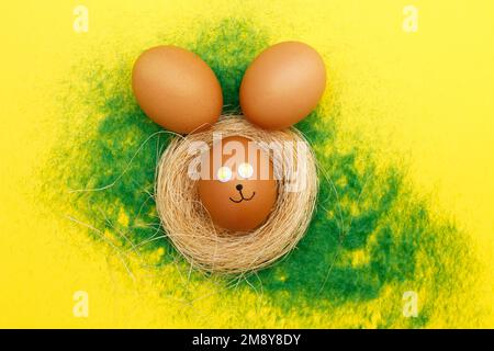 happy easter bunny eggs in nest on the decorative grass on a yellow background. copy space for text Stock Photo