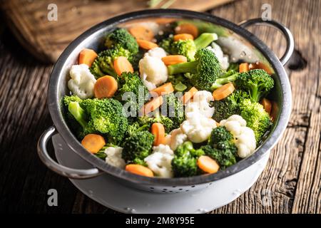 Steamed broccoli, carrots and cauliflower in a stainless steel steamer. Healthy vegetable concept. Stock Photo