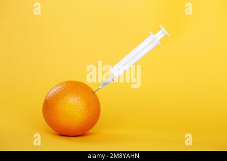 orange fruit with syringe extracting liquid with vitamin C. natural anti aging cosmetics concept. Stock Photo