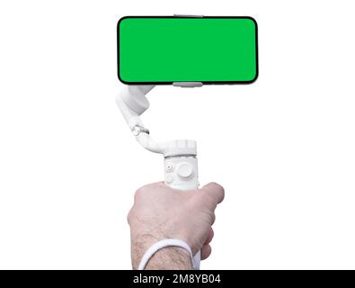 Electronic stabilizer for smartphone in human hand. Isolated green screen with chroma key. Hand holds 3 axis gimbal stabilizer isolated. Gimbal close Stock Photo