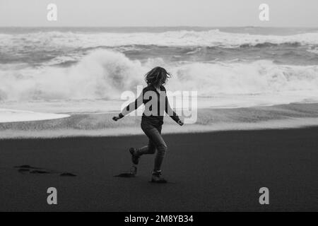 Tourist running along Reynisfjara beach monochrome scenic photography Stock Photo