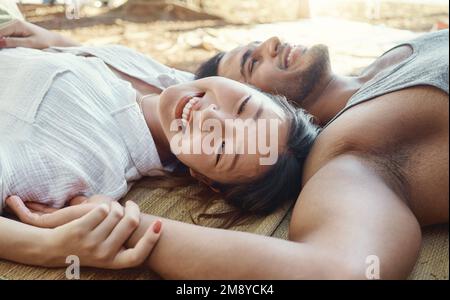 Nature allows us to connect deeper. a young couple lying down and bonding during a camping trip in the woods. Stock Photo
