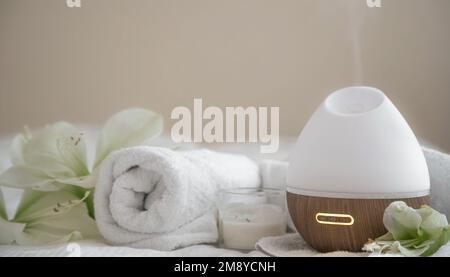 Cozy spa composition with aroma diffuser, candle and flowers. Stock Photo