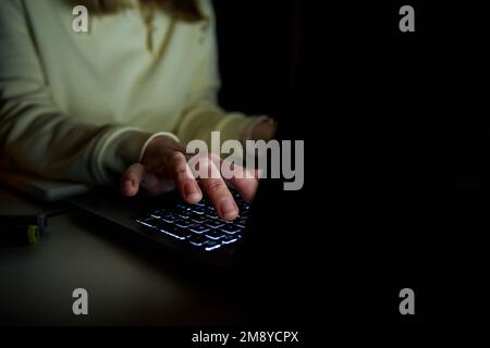 Close up shot of anonymous woman typing on laptop keyboard at night. Online communication and working after hours concept Stock Photo