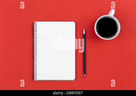 Blank notepad, coffee cup and pencil on red background, flat lay. Stock Photo