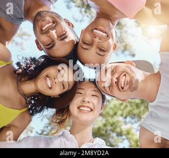 Bonding in nature makes our bond stronger. Low angle shot of a diverse group of friends standing huddled together during a day in the woods. Stock Photo