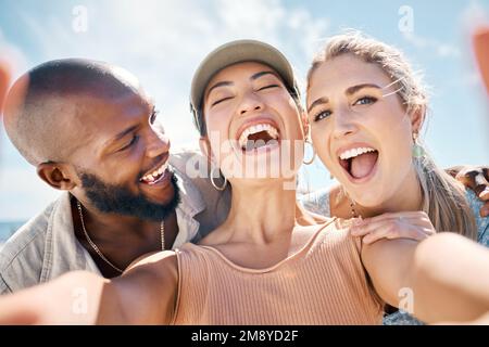 Happiness looks good on us. a diverse group of friends standing outside together and taking selfies. Stock Photo