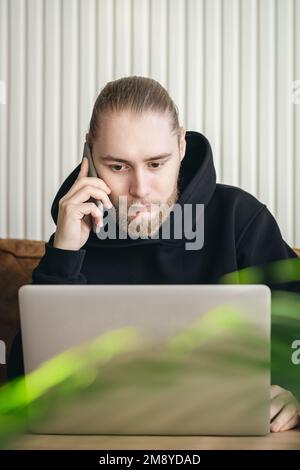 An attractive young man with a beard is working on a laptop. Stock Photo