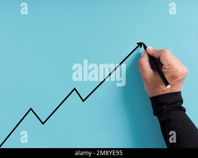 Business or economic growth and development concept. Hand draws an ascending line on blue background. Stock Photo