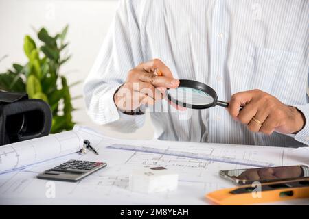 Architectural interior designer working holding magnifying glass and look on blueprint Stock Photo