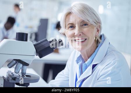 She always finds something amazing. a mature scientist using a microscope in her lab. Stock Photo