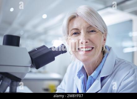 Science is an ever evolving field. a mature scientist using a microscope in her lab. Stock Photo
