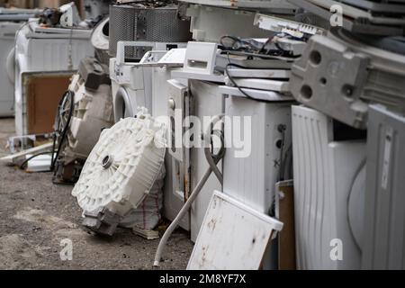 Dump or collection point for broken washing machines and spare parts on ground in open air Stock Photo