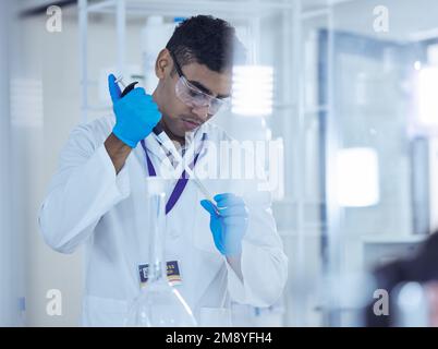 Slow and steady. a male scientist decanting samples into test tubes. Stock Photo