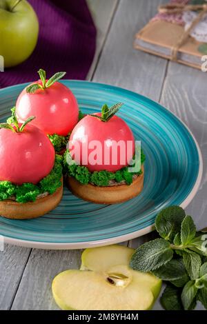 Apple shaped mousse dessert in pink glaze on shortcrust tartlets Stock Photo