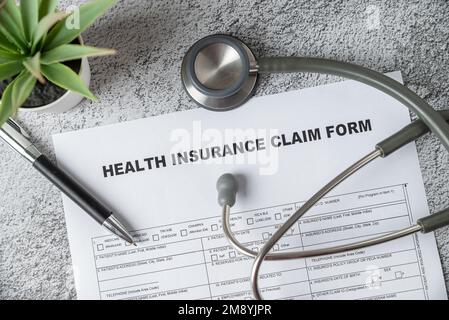 Top view of doctor's stethoscope, pen and health insurance claim form on table Stock Photo