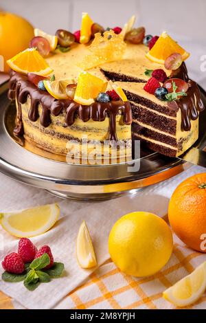 Chocolate sponge cake with citrus custard, ganache, oranges, lemon and berries Stock Photo