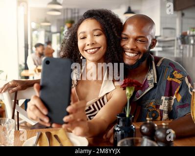 These are the moments that matter. a young couple on a date at a restaurant taking selfies using a cellphone. Stock Photo