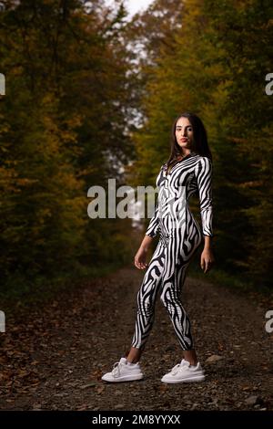 A Caucasian woman wearing black and white costume and looking at camera in forest Stock Photo