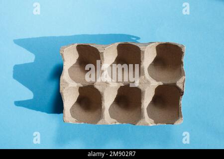 Empty eggs carton box with hard shadows on blue background Stock Photo