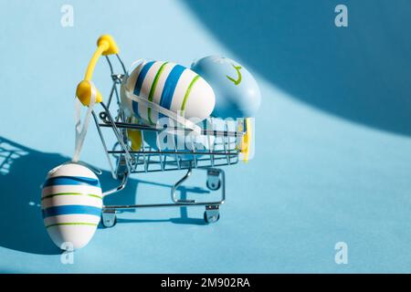 Easter eggs in the shopping cart on a blue background. Stock Photo