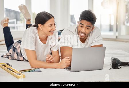 What do you prefer. a young couple lying on their living room floor and using a laptop. Stock Photo