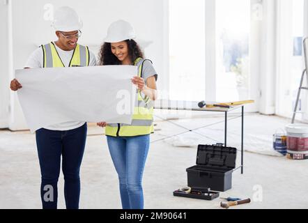 This is the customers plan. two young contractors standing inside together and looking at building plans. Stock Photo