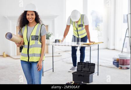 Renovations are our speciality. an attractive young contractor standing inside and holding building plans. Stock Photo