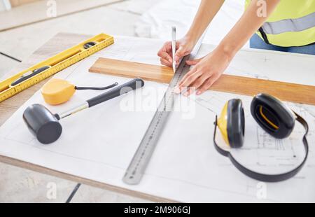 Adding a homely touch. an unrecognisable contractor standing alone inside and using a ruler to draw up building plans. Stock Photo