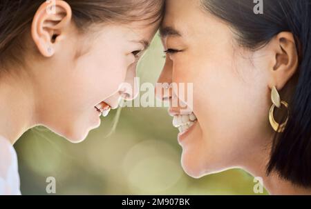Be the reason she smiles. an adorable little girl and her mother looking at each other face to face in a garden. Stock Photo