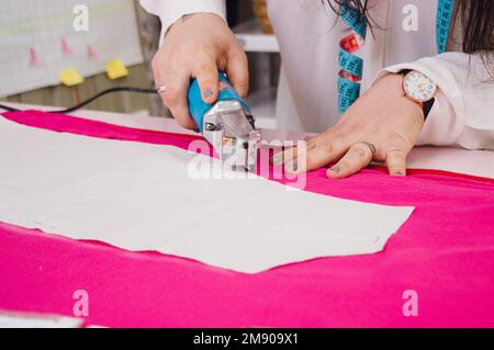 unrecognizable caucasian woman in her home workshop working cutting fabric with manual mechanical cutter, sewing concept, copy space. Stock Photo