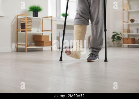 Young man with broken leg or foot injury is undergoing rehabilitation at home. Stock Photo