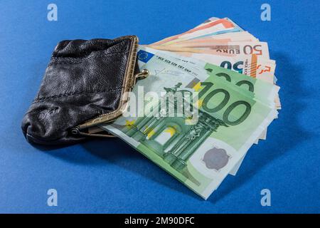 Black wallet with money isolated on blue background. Stock Photo