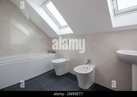 Contemporary modern attic style fitted bathroom with sloping ceiling and black tiled floor Stock Photo