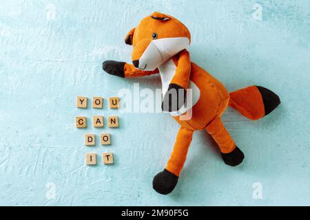 You can do it, motivational banner with a toy fox on a blue background, inspirational saying, a flat lay Stock Photo