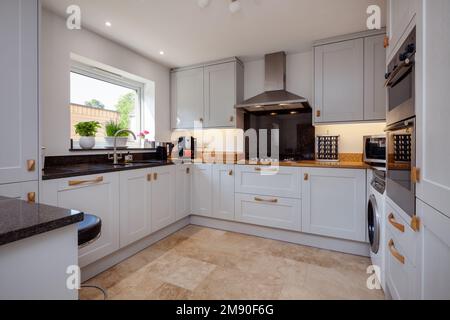 Modern contemporary shaker style fitted kitchen with built in appliances breakfast bar and granite counbter tops Stock Photo