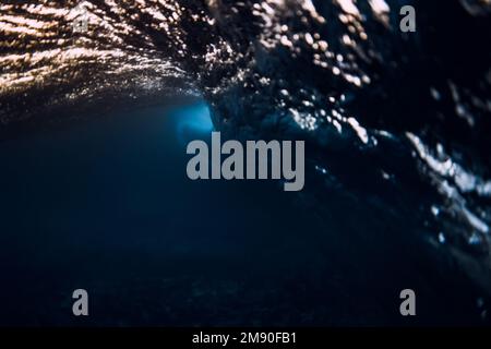 Barrel wave crash in ocean with warm sunset or sunrise tones. Underwater background with surfing wave Stock Photo