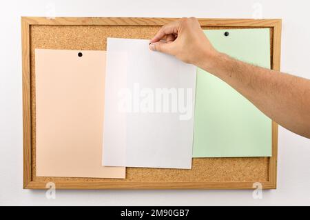 Businessman hands pin sticky notes on cork bulletin board at office Stock Photo