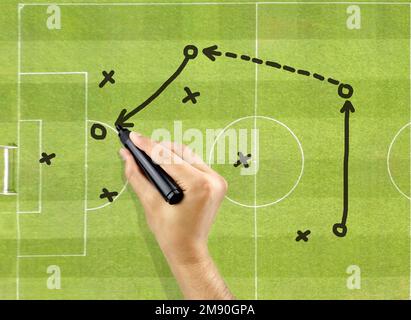 hand of a football coach drawing a tactics of soccer game with black pen on field background Stock Photo