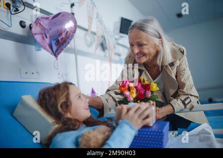 Granmother visiting her sick granddaughter in hospital, celebrating her birthday. Stock Photo