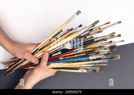 Paint brushes in male hands on a colored background, top view. Stock Photo
